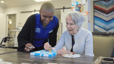 A staff member and resident work together on a table activity at Arbor Terrace Glenview senior living, embracing the active senior lifestyle Glenview provides.